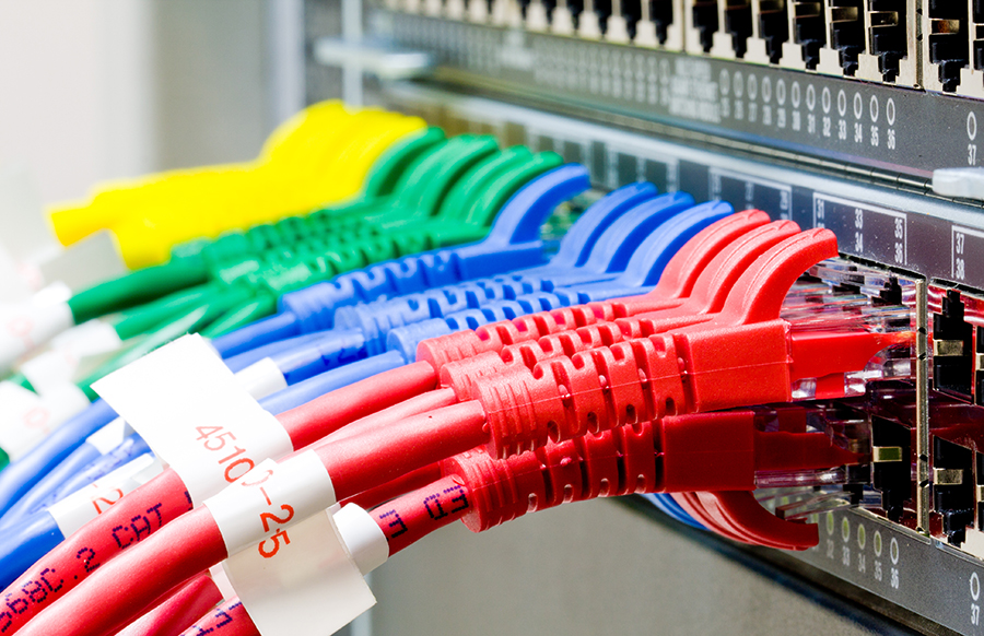 A technician organizing structured network cables in a server rack.